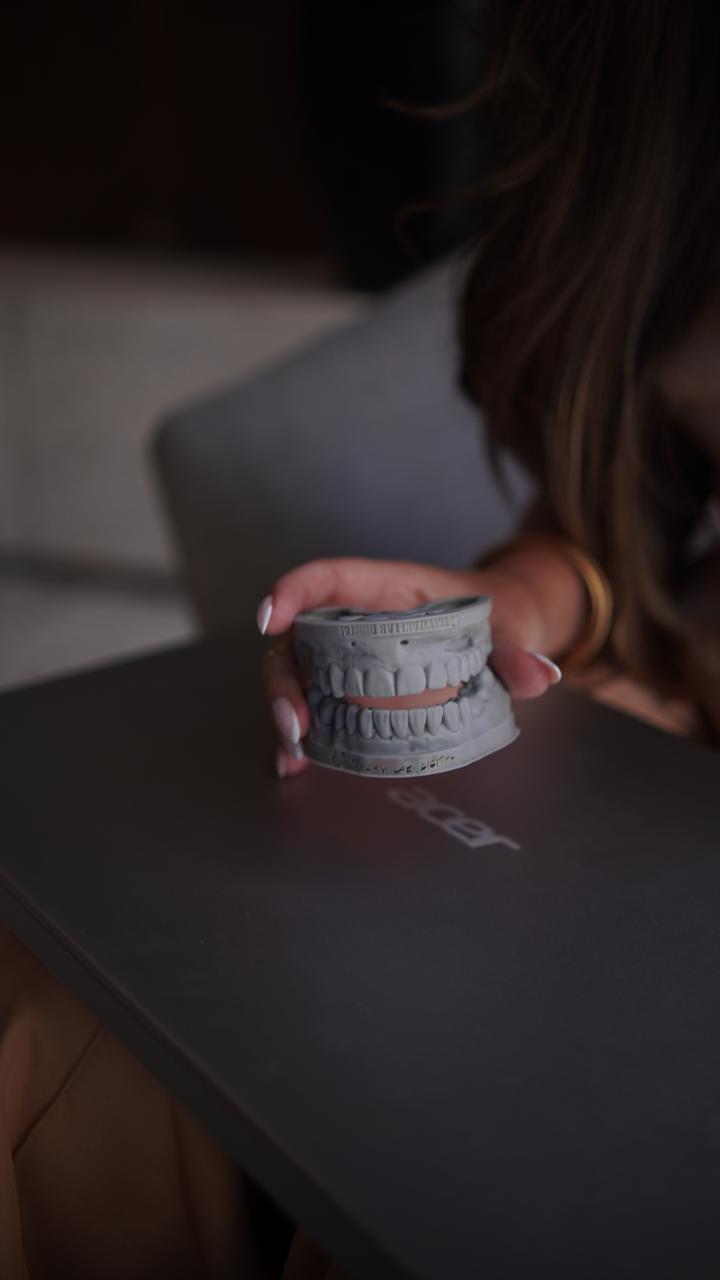 Modelo de arcada dentária em cima do laptop, DENTRO da clínica